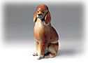 This stately sitting tan oodle figurine calmly looks at you with bright black eyes.